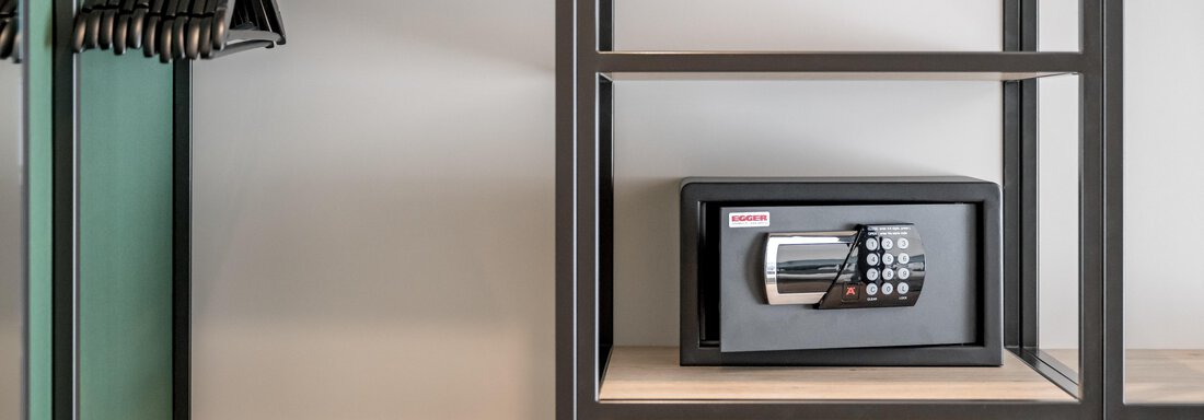 A modern cabinet with a digital safe on a shelf. Beside the safe, there are hangers. - The Moss - Your unique hideaway - Obergurgl 