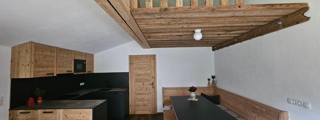 Wohnküche Rosa A modern kitchen with wooden details and a dining area. The open space concept offers plenty of light and room. - Almhof Mareil - Ochsengarten