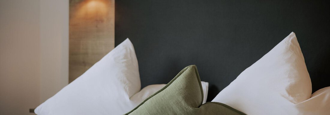 _F0A6717 Ein gemütliches Schlafzimmer mit einem großen Bett und weißen Kissen. Eine schlichte Nachttischlampe sorgt für warmes Licht. - Apartment Waldesruh - Ochsengarten