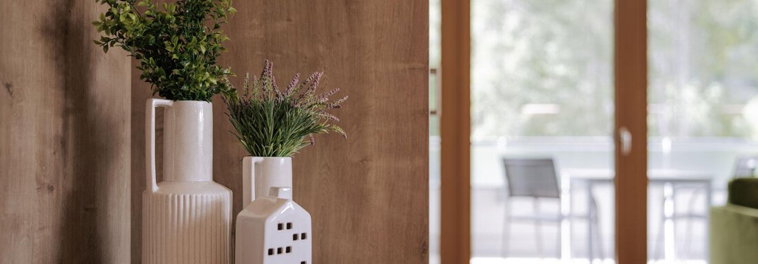 Eine stilvolle Wohnung mit Holzverkleidung und modernen Dekorationen. Im Vordergrund stehen Vasen mit Pflanzen auf einem Tisch. - Apartment Waldesruh - Ochsengarten