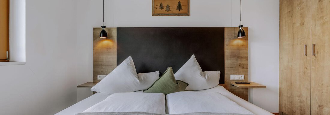 Ein gemütliches Schlafzimmer mit einem Doppelbett und modernen Schränken. Die Wände sind hell, und die Beleuchtung sorgt für eine entspannte Atmosphäre. - Apartment Waldesruh - Ochsengarten
