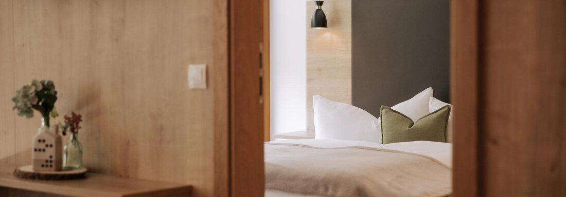 _F0A6941 Ein gemütliches Schlafzimmer mit einem großen Bett und sanften Farben. Im Hintergrund ist ein Fernseher und eine dekorative Pflanze sichtbar. - Apartment Waldesruh - Ochsengarten