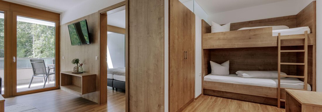 Ein modernes Zimmer mit Holzverkleidung und einem Stockbett. Es gibt einen Fernseher und einen Balkon mit Blick ins Freie. - Apartment Waldesruh - Ochsengarten