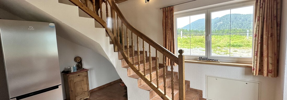 A cozy living kitchen with a wooden staircase. Large windows offer a view of the surrounding nature. - Ferienhaus Föger - Ochsengarten