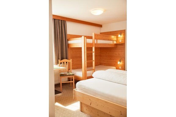 Ein helles Zimmer mit Holzverkleidung und Etagenbett. Es gibt ein Einzelbett und einen Tisch mit einem Stuhl. - Gasthof Walderhof - Ochsengarten