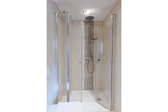 Eine moderne Dusche mit Glasscheiben und einer Regendusche. Die Wände sind in neutralen Farben gehalten. - Gasthof Waldesruh - Ochsengarten