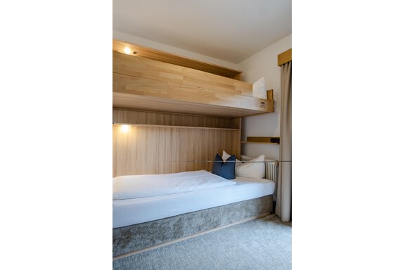 Ein modernes Schlafzimmer mit zwei Betten. Das obere Bett ist ein Hochbett aus Holz, während das untere Bett eine gemütliche Schlafgelegenheit bietet. - Gasthof Waldesruh - Ochsengarten