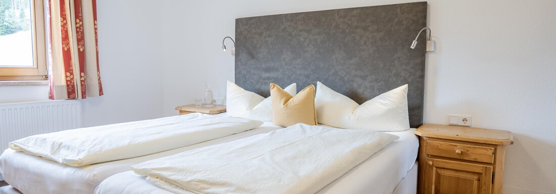Ein gemütliches Schlafzimmer mit zwei Betten und weißen Bettdecken. An der Wand hängt ein Bild, und es gibt einen Holztisch neben dem Bett. - Gasthof Waldesruh - Ochsengarten