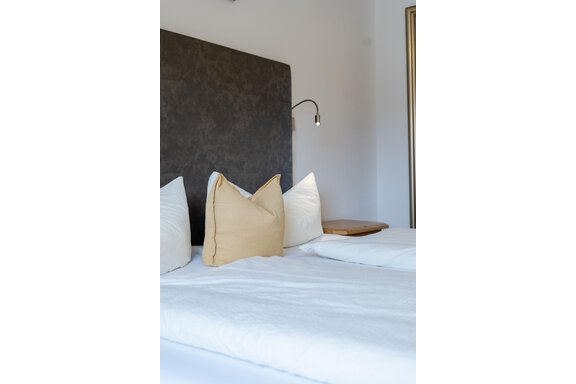 Ein modernes Schlafzimmer mit zwei Betten und Kissen. Die Wände sind hell und es gibt eine Leselampe an der Wand. - Gasthof Waldesruh - Ochsengarten