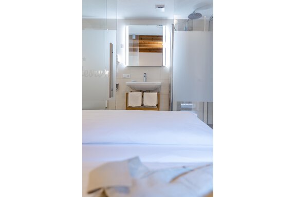 Ein modernes Schlafzimmer mit einem klaren Blick auf das Badezimmer. Die Ausstattung ist minimalistisch und elegant. - Gasthof Waldesruh - Ochsengarten