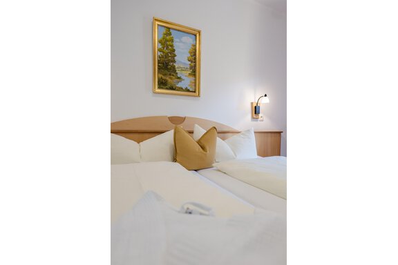 Ein gemütliches Schlafzimmer mit zwei Betten und weißen Kissen. An der Wand hängt ein Malerei mit einer Landschaft. - Gasthof Waldesruh - Ochsengarten