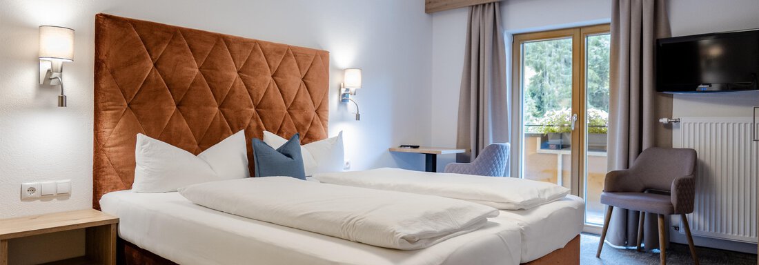 Ein modernes Hotelzimmer mit einem Doppelbett und gemütlicher Einrichtung. Große Fenster sorgen für viel Tageslicht. - Gasthof Waldesruh - Ochsengarten