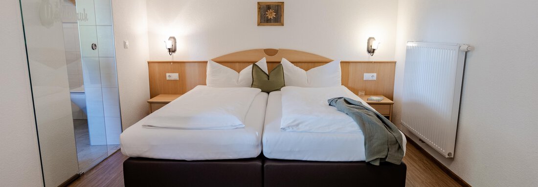 Ein gemütliches Hotelzimmer mit zwei Einzelbetten und hellen Wänden. Das Zimmer ist modern eingerichtet und verfügt über sanfte Beleuchtung. - Gasthof Waldesruh - Ochsengarten