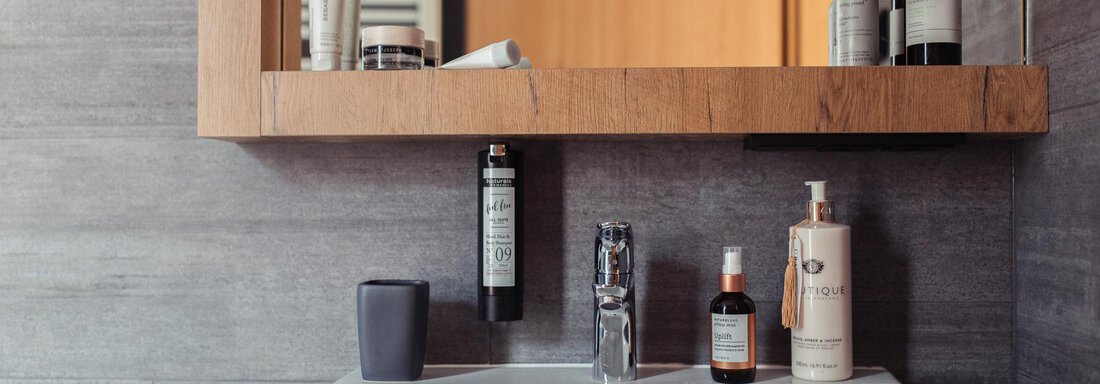 A modern bathroom with a square sink and stylish toiletries. Wooden elements and gray tiles create an elegant atmosphere. - All-Suite Resort Ötztal - Oetz