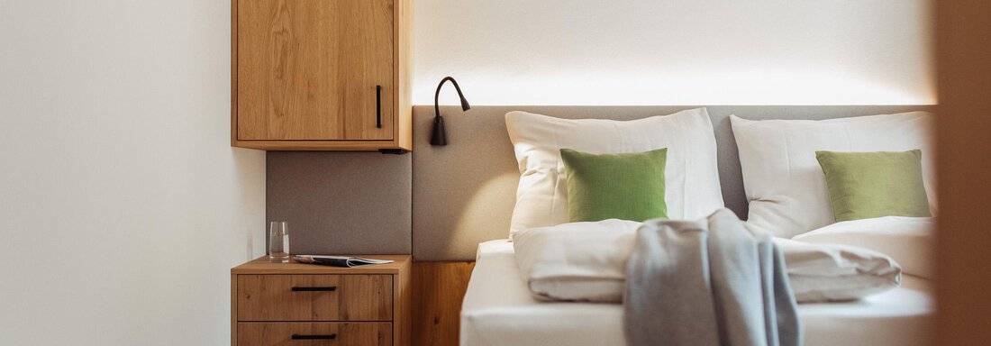 A modern bedroom with a cozy bed and natural wooden furniture. The soft lighting creates a relaxed atmosphere. - All-Suite Resort Ötztal - Oetz