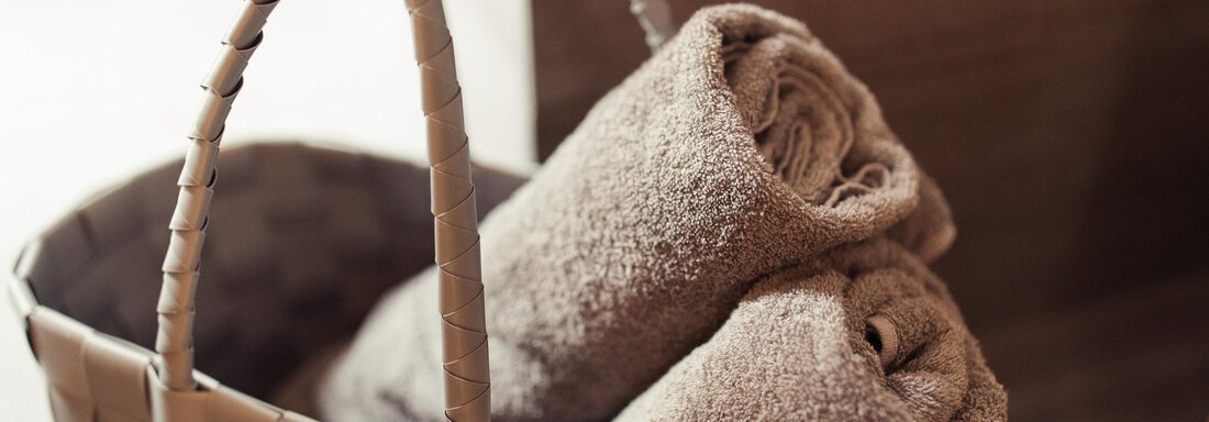 A laundry basket with rolled towels. The towels are brown and soft. - All-Suite Resort Ötztal - Oetz