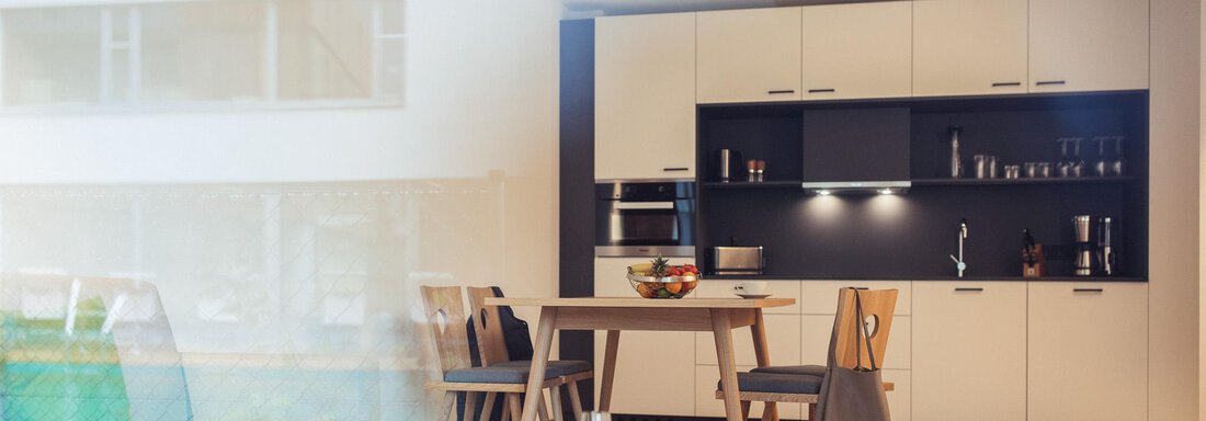 A modern kitchen with a dining table and a cozy chair. The room offers a bright and inviting atmosphere. - All-Suite Resort Ötztal - Oetz