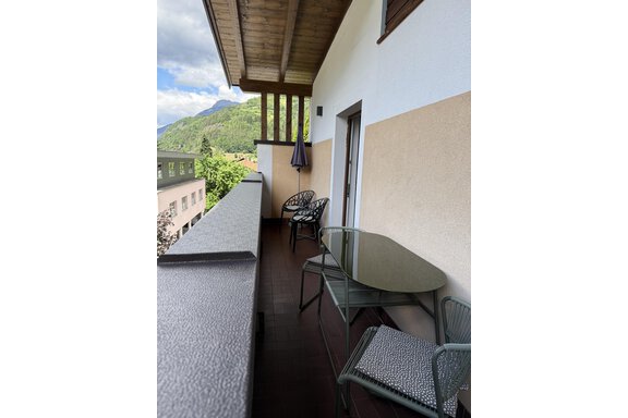 A balcony with a table and several chairs. In the background, there are mountains and a blue sky. - Appartements Schmid Peter - Oetz