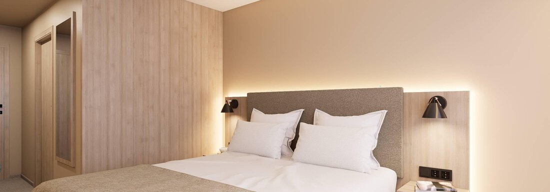 Ein modernes Schlafzimmer mit einem Doppelbett und minimalistischer Einrichtung. Die Wände sind hell, und es gibt eine angenehme Beleuchtung. - Hotel Marko - Oetz