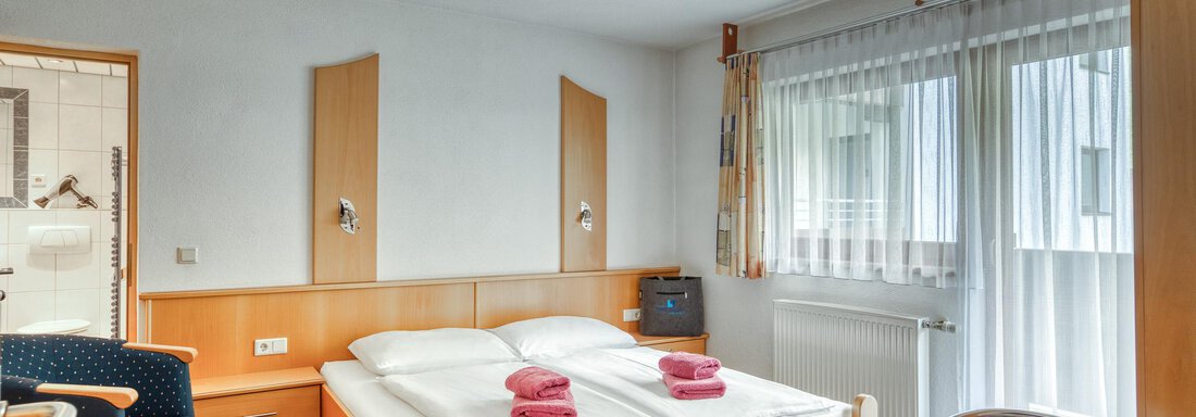 20250512 Seehüter's Fuchsloch 1 A cozy hotel room with a double bed and two armchairs. Large windows provide plenty of daylight. - Seehüter´s Hotel Seerose - Oetz