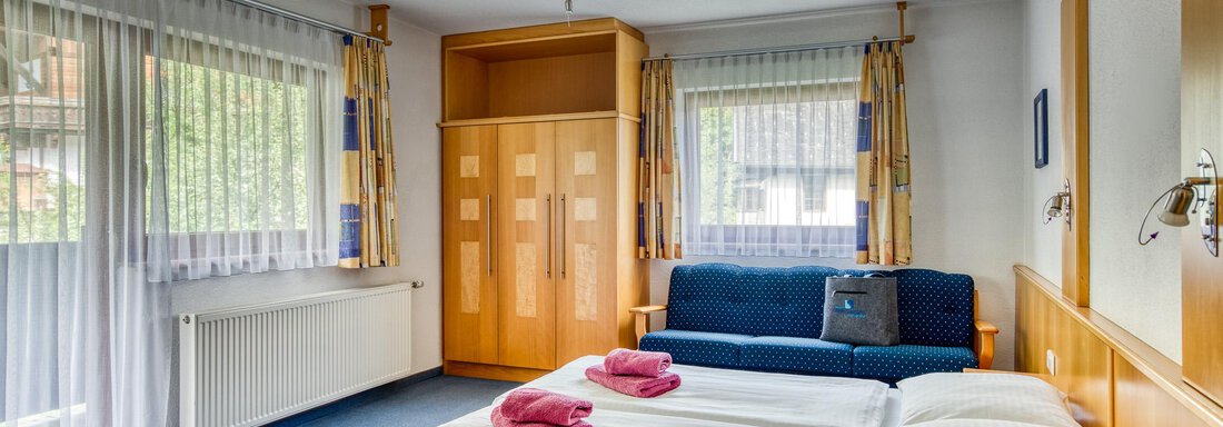 20250512 Seehüter's Kluft 1 A cozy hotel room with a double bed and a sofa.
Large windows and wooden furniture create a friendly atmosphere. - Seehüter´s Hotel Seerose - Oetz