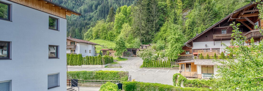 A picturesque landscape with green mountains and modern buildings. The surroundings are peaceful with trees and a well-kept lawn. - Seehüter´s Hotel Seerose - Oetz
