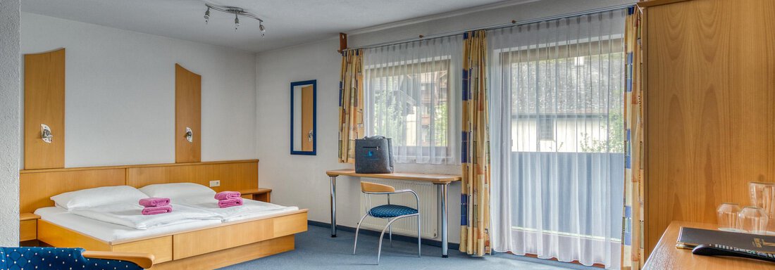 20250512 Seehüter's Bergsee 2 A bright hotel room with two single beds and a cozy armchair. There is a table with a chair and large windows that let in plenty of light. - Seehüter´s Hotel Seerose - Oetz