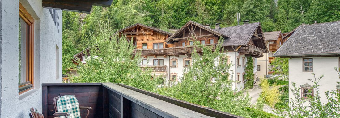 A balcony with two chairs and a view of a picturesque village in the mountains. Surrounded by trees and a bright blue sky. - Seehüter´s Hotel Seerose - Oetz