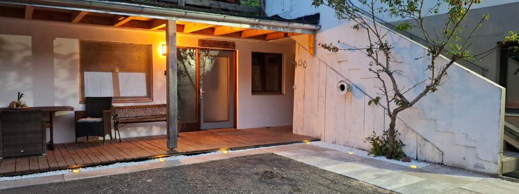 A cozy entrance to a modern building with a wooden porch. The soft lighting creates an inviting atmosphere. - Appartement Harmony - Sautens