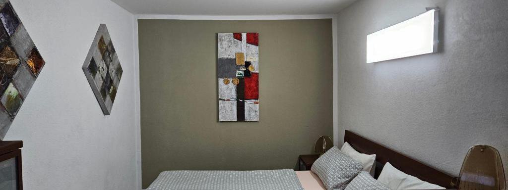 A cozy bedroom with a double bed and decorative pillows. Modern artwork hangs on the walls, and there is soft lighting. - Appartement Harmony - Sautens