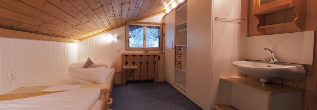Ein gemütliches Zimmer mit Holzvertäfelung und zwei Einzelbetten. Der Raum hat ein Fenster mit Aussicht und eine kleine Waschecke. - bei Herrmann´s - Sautens