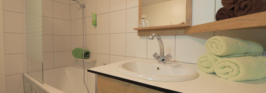 Das Badezimmer ist modern und stilvoll eingerichtet. Es gibt eine Badewanne, ein Waschbecken und saubere Handtücher in verschiedenen Farben. - bei Herrmann´s - Sautens