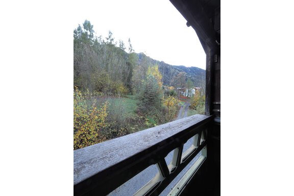 Ein Blick aus einem Fenster auf eine grüne Landschaft mit Bäumen und Hügeln. Der Weg führt durch die malerische Umgebung. - bei Herrmann´s - Sautens