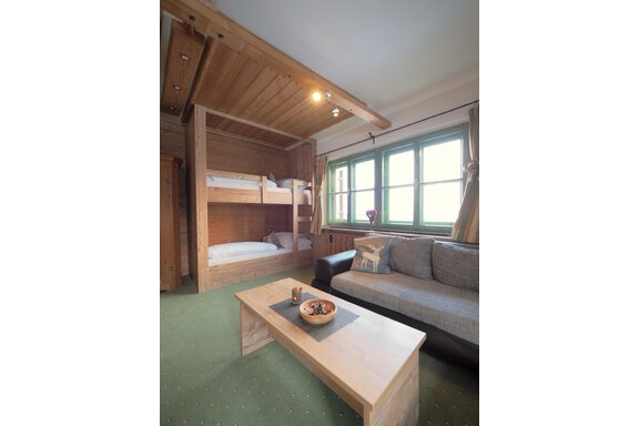 Ein gemütliches Zimmer mit einem Etagenbett und einem Sofa. Große Fenster lassen viel Licht herein und sorgen für eine einladende Atmosphäre. - bei Herrmann´s - Sautens