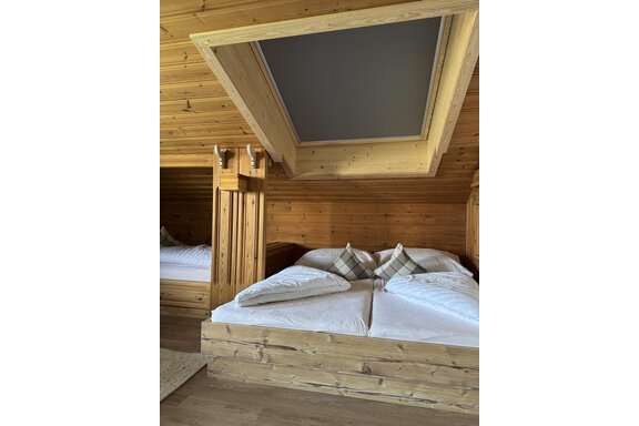 Ein gemütliches Schlafzimmer mit Holzverkleidung und zwei getrennten Betten. Über dem Bett befindet sich ein Dachfenster, dieses kann komplett abgedunkelt werden. - bei Herrmann´s - Sautens