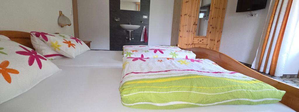 A cozy bedroom with a double bed and colorful cushions. The room is bright and friendly, with modern decor and a large window. - Ferienhof Strigl - Sautens