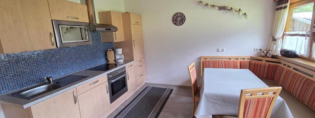 Küche 2. Obergeschoss A bright kitchen with wooden shelves and modern appliances.
At a table with colorful chairs, one can sit comfortably. - Ferienhof Strigl - Sautens