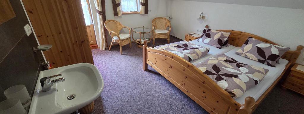 A cozy bedroom with a double bed and elegant bed linens. The room is bright and has wooden details as well as two chairs. - Ferienhof Strigl - Sautens