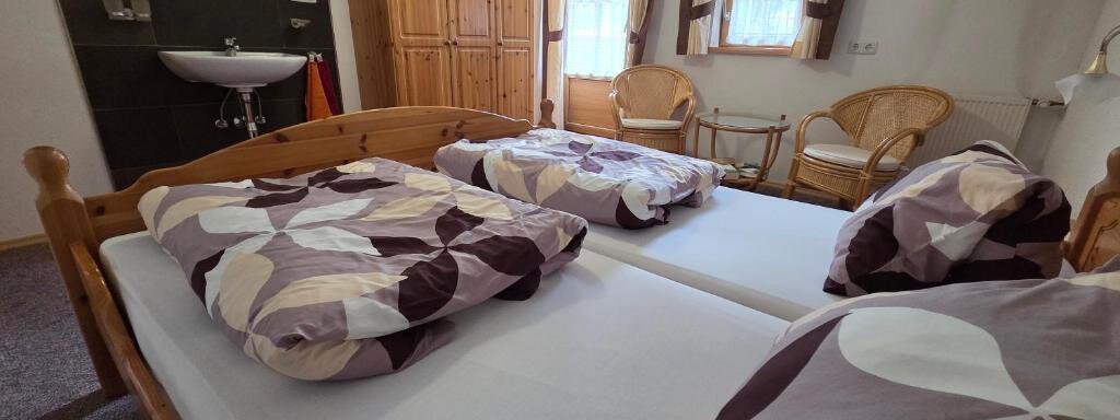 A cozy room with two single beds and colorful bed covers. Large windows provide plenty of daylight and there is a wooden wardrobe and two chairs. - Ferienhof Strigl - Sautens