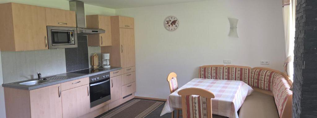 Küche 1. OG A modern kitchen with wooden cabinets and a kitchen table. The seating area consists of an L-shaped bench and chairs. - Ferienhof Strigl - Sautens