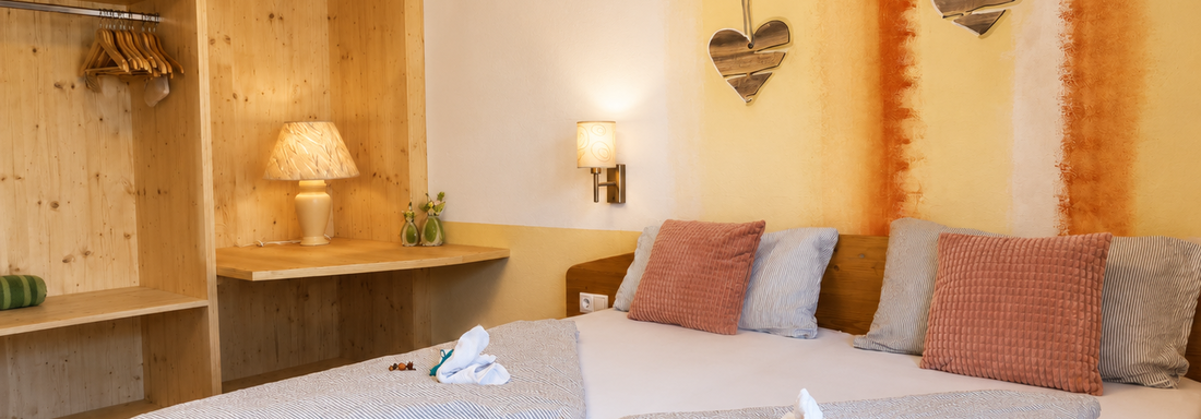 A cozy bedroom with two beds and stylish decorations. The warm wood elements and soft light create an inviting atmosphere. - Gästehaus Fernblick - Sautens