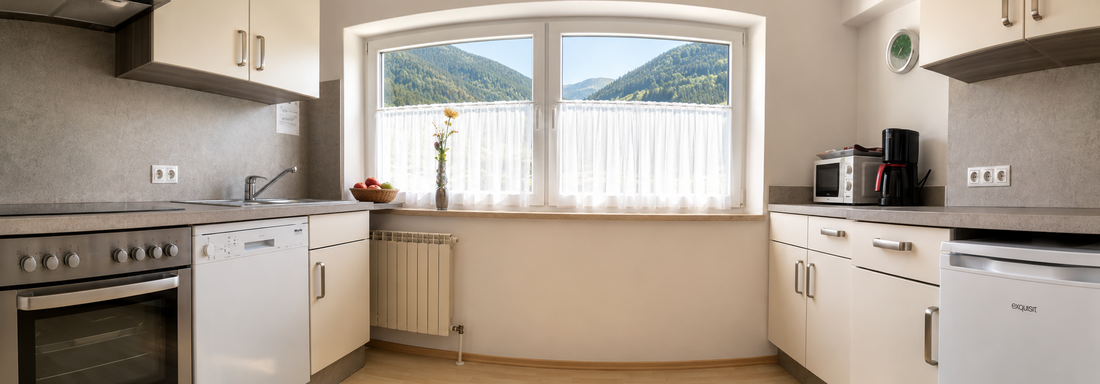 A modern kitchen with bright cabinets and a large window that offers a view of the mountains. The space feels friendly and inviting. - Gästehaus Fernblick - Sautens