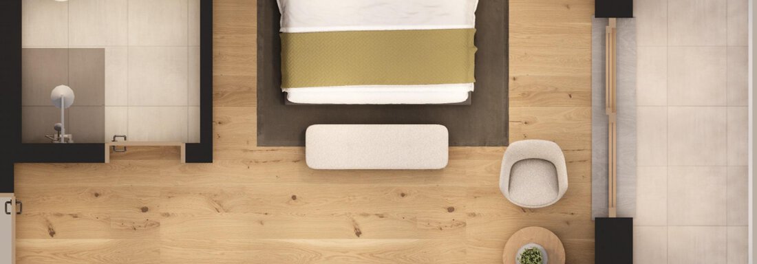 A modernly furnished room with a large bed and wooden floor. There are additional pieces of furniture like an armchair and a table that create a cozy atmosphere. - A CASA "Aventurin" - Sölden