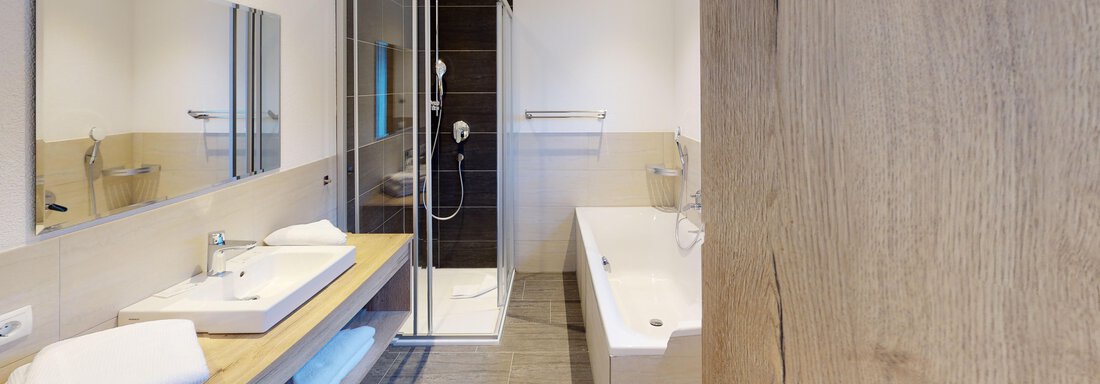 A modern bathroom with a floor shower and a freestanding bathtub. Bright colors and wooden details create an inviting atmosphere. - A CASA "Rubin Chalet & Studio Resort" - Sölden