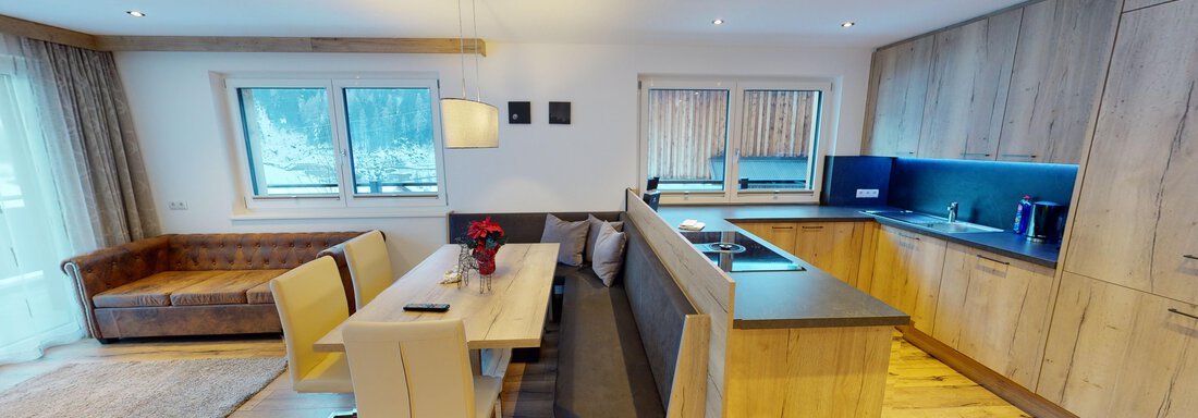 A modern apartment with a cozy dining area and an open kitchen. Bright wooden furniture creates an inviting atmosphere. - A CASA "Rubin Chalet & Studio Resort" - Sölden