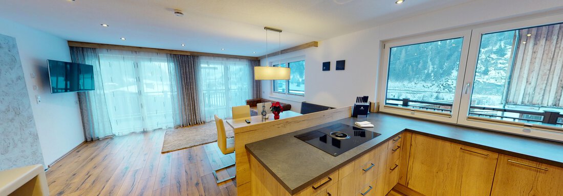 A modern apartment with an open living and kitchen area. Large windows offer a view of the surrounding mountains. - A CASA "Rubin Chalet & Studio Resort" - Sölden
