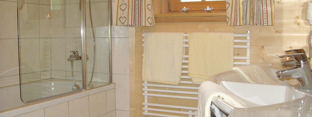 A modern bathroom with a shower and bathtub. The walls are made of light wood and there are terry towels. - Almdorf Waldesruh - Sölden