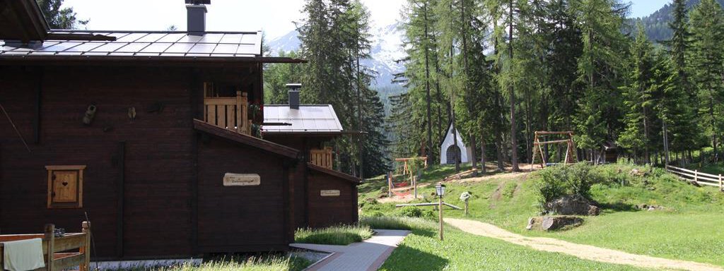A peaceful landscape with wooden houses and a beautiful path. Surrounded by trees and mountains, the environment invites relaxation. - Almdorf Waldesruh - Sölden