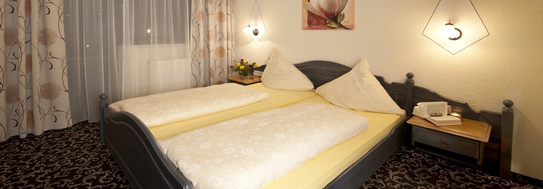 A cozy bedroom with a large double bed and two pillows. The walls are painted in soft colors, complemented by stylish decorations and curtains. - Alp Resort Tiroler Adler - Sölden