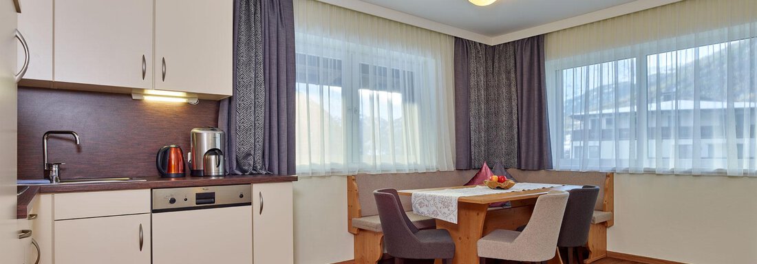 Alpenrose/Silberdistel A modern living room with a kitchen corner and a dining table. Large windows provide plenty of light and a welcoming space. - Alp Resort Tiroler Adler - Sölden